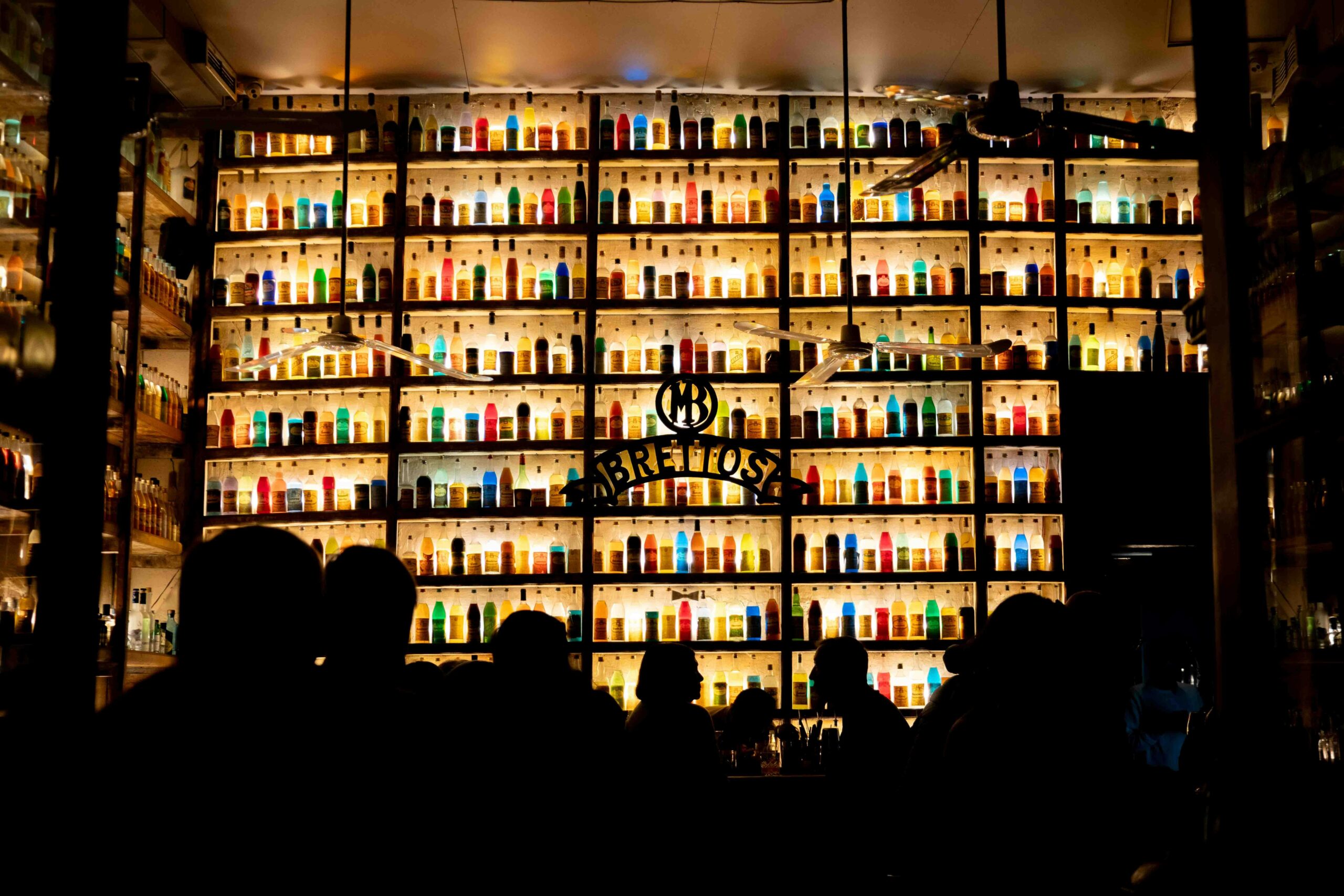 Colorful bar scene showcasing bottles and silhouettes in Athens, Greece nightlife.